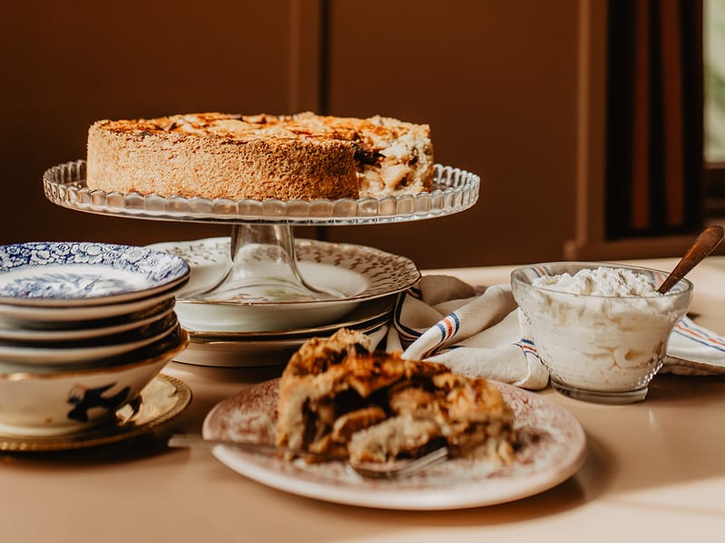 Appeltaart op een taartschaal met stapels borden