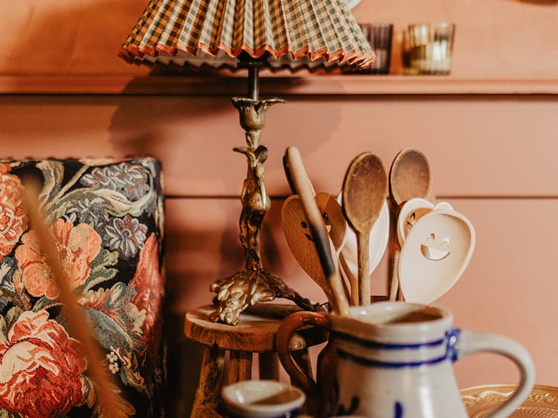 A table lamp and wooden spoons beside the flowered chair