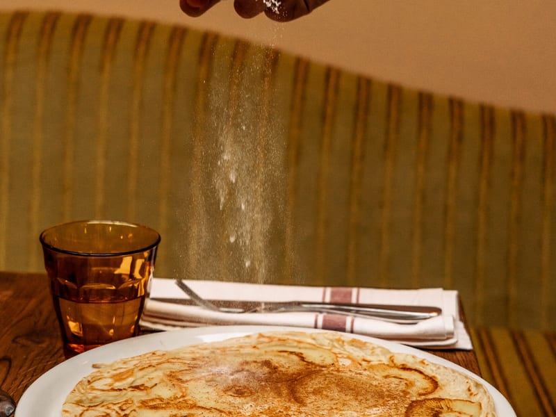 Icing sugar over a plain pancake