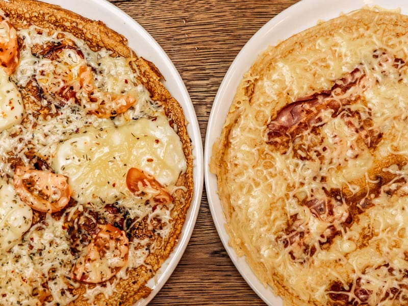 Twee pannenkoeken, hartig en met kaas, op de houten tafel