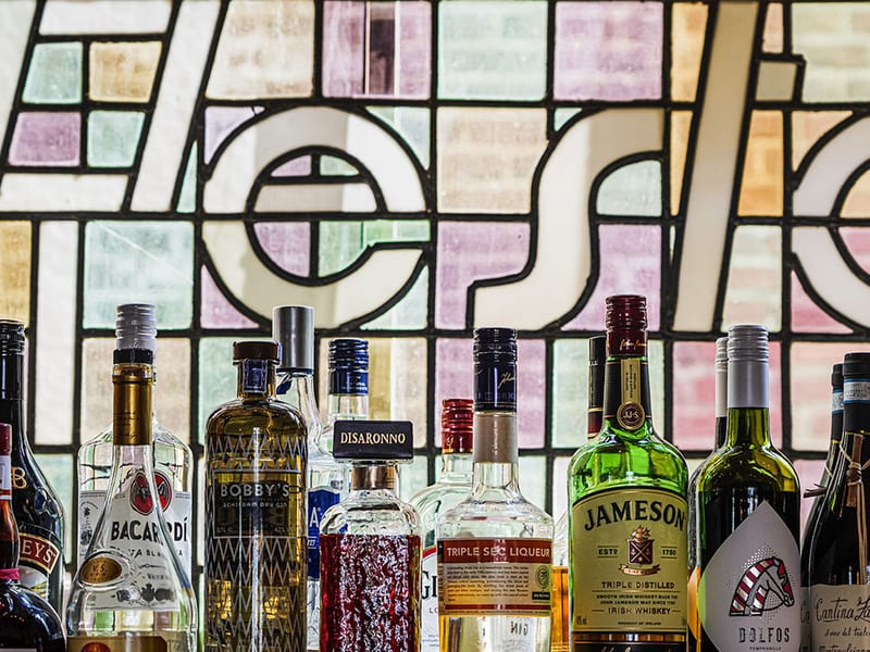 Bottles in front of the leaded glass window behind the bar
