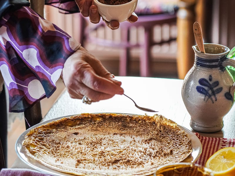 Een pannenkoek met suiker en stroop, met een Delftse kruik ernaast