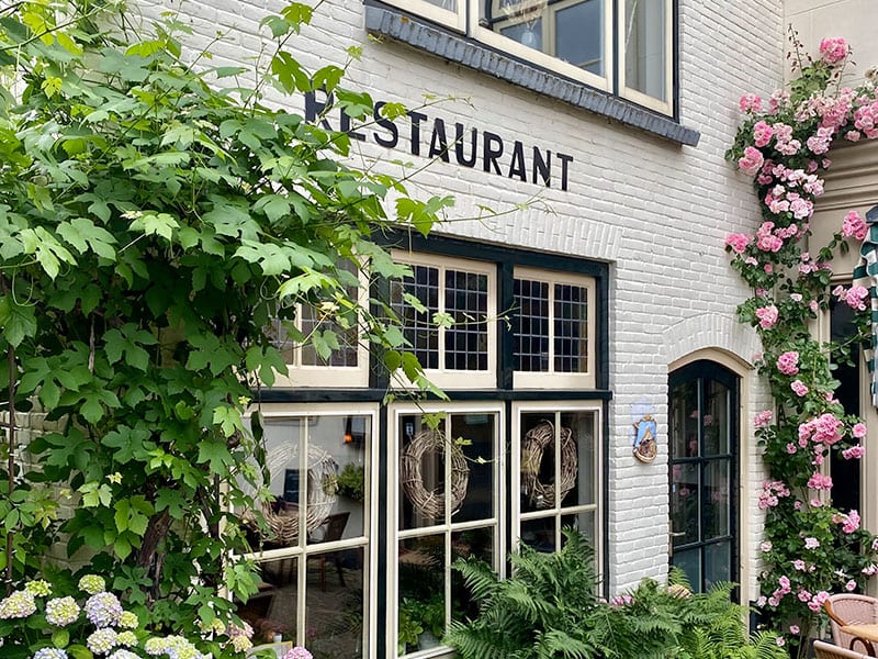 De gevel met het opschrift RESTAURANT, overwoekerd met groen