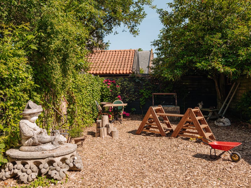 The garden with the wishing well, the garden house and a red wheelbarrow