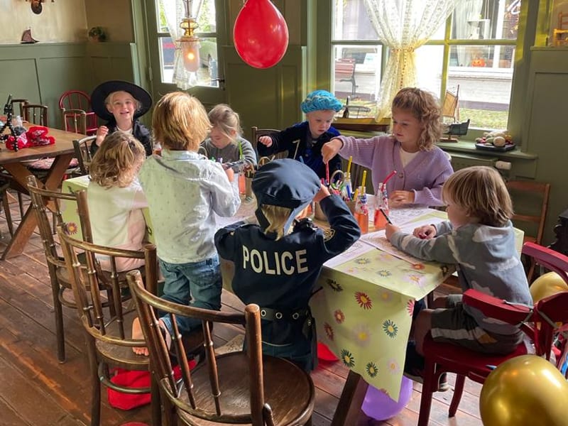 Kinderen aan een lange tafel tijdens een kinderfeestje