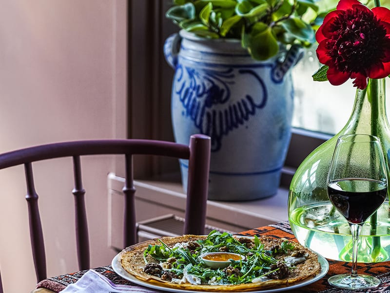Een pannenkoek met rucola en geitenkaas bij het raam
